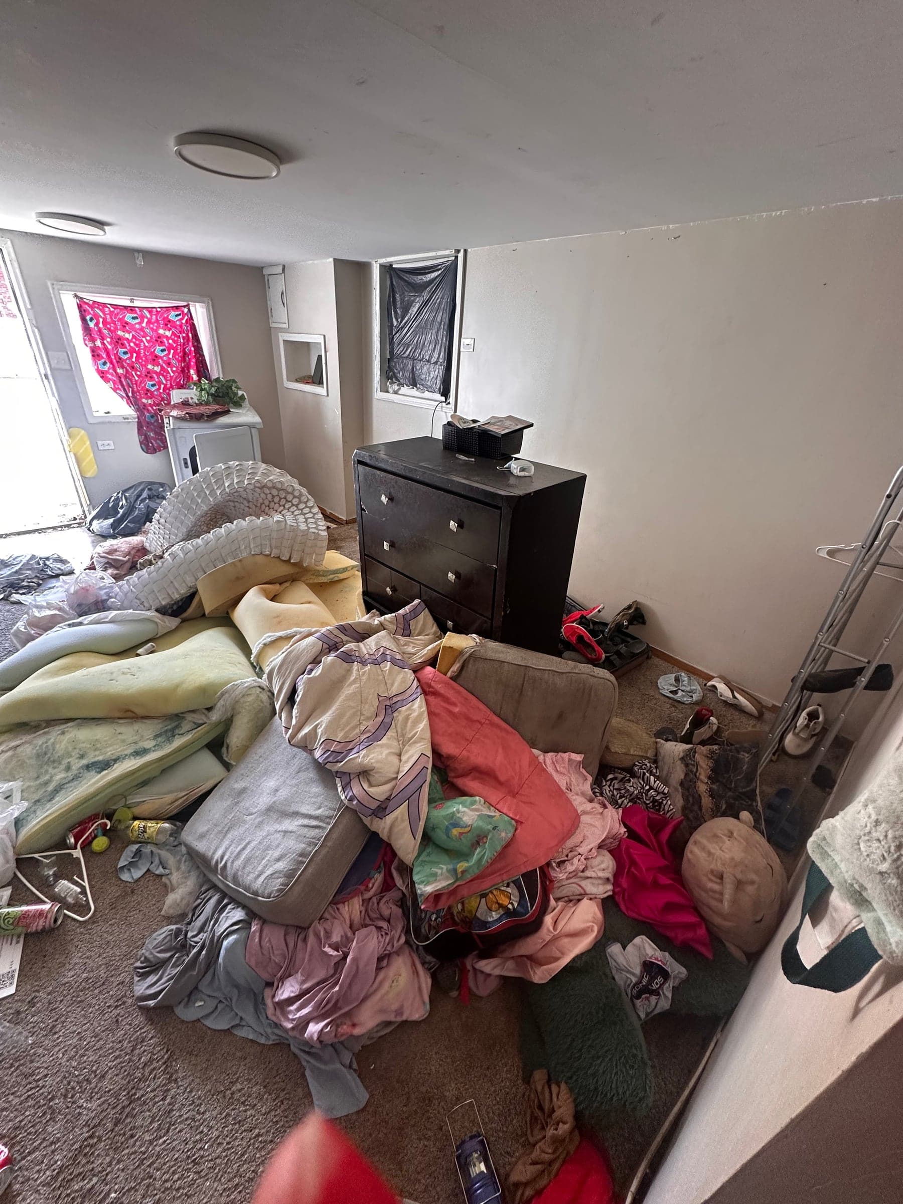 A bedroom piled with clothes and bedding before a house cleanout