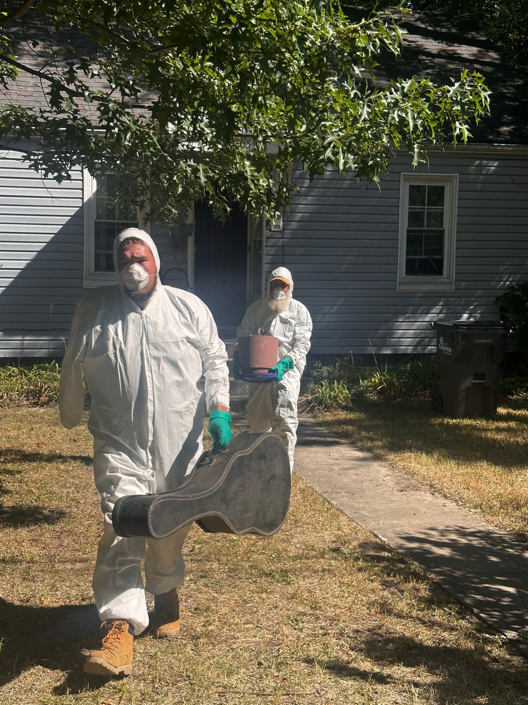 Cole & Isy carrying a chair out of a house cleanout