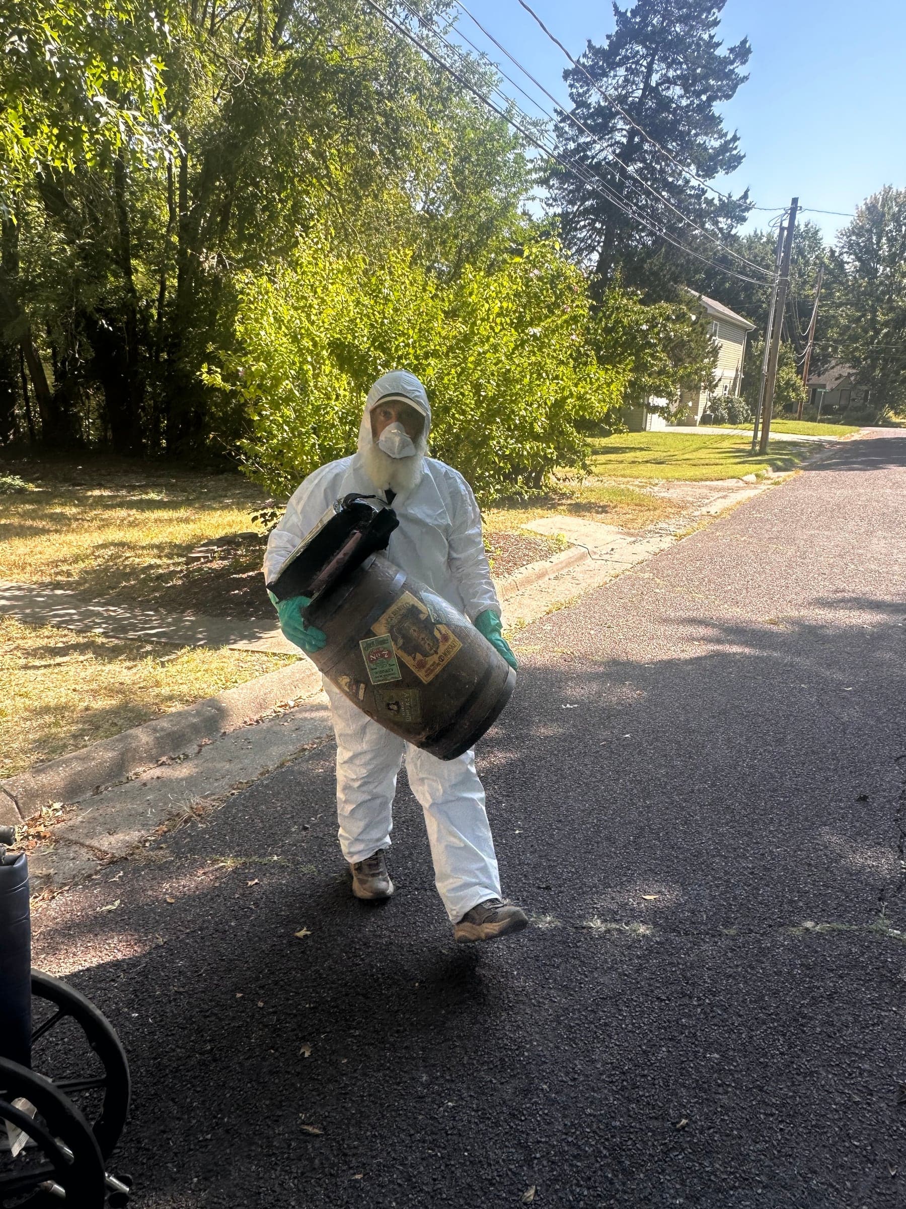 A crew member in a protective suit carrying a load to the street