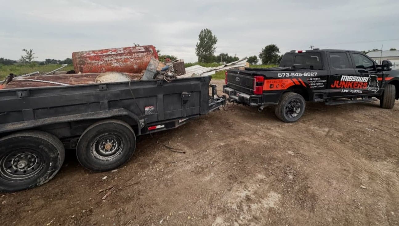 Missouri Junkers' wrapped F-250 towing a dump trailer loaded with scrap metal on a job site near Moberly, MO