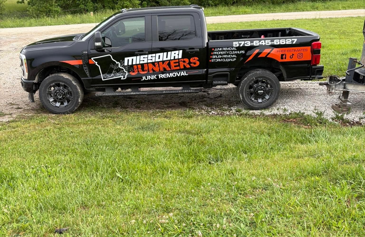 Missouri Junkers black F-250 with orange wrap parked on a gravel drive