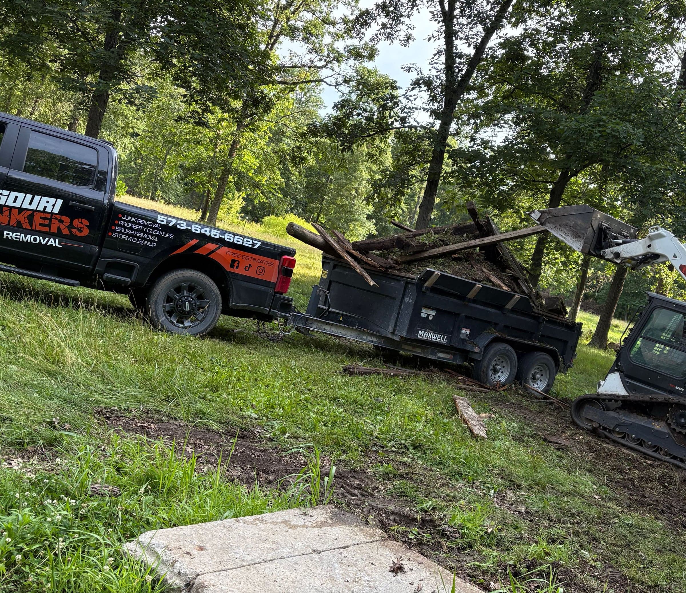 The Missouri Junkers truck and dump trailer with a skid steer loading limbs